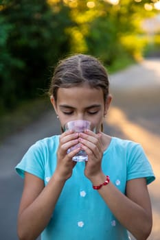 A child drinks water from a glass. Selective focus. Kid.