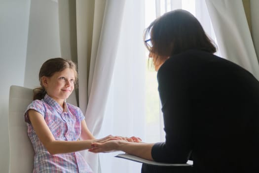 Woman social worker psychologist talking to girl child in office. Children mental health