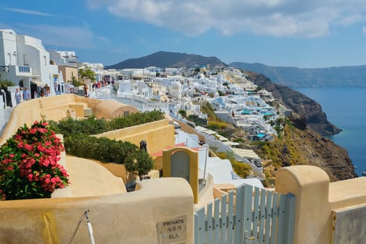 11.09.2019, Greece, Santorini, Oia. Famous Greek island of Santorini, popular tourist village Oia. Traditional white architecture, sea, mountains, sky and many tourists walking and resting people