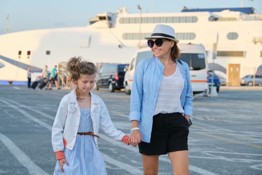 Mother and daughter child walking along seaport, family sea trip, summer vacation. Sea transport, ferry at port background