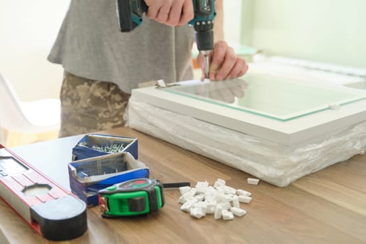 Closeup of hand worker doing furniture, assembling kitchen with professional tools