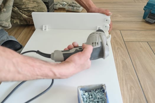 Furniture assembly. Closeup of workers hand with professional tools and furniture details