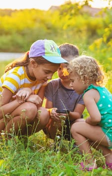 Children look through a magnifying glass together at the plants in the garden. Selective focus. Kid.