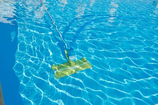 Close-up of outdoor swimming pool underwater, cleaning vacuum tube.