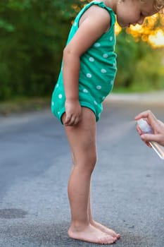 Mom sprays her child with mosquito repellent. Selective focus. Nature.