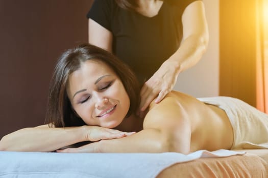 Professional back massage procedure, adult woman receiving treatment lying on massage table