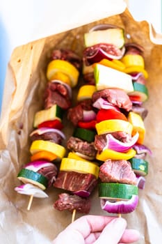 Raw skewers with beef and fresh veggies, wrapped in butcher brown paper, await grilling.