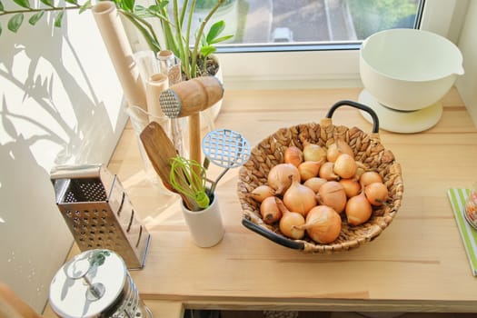 Kitchen pantry interior with groceries and utensils. Basket with golden onions on wooden table in the kitchen