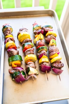 Flavorful beef and colorful veggie skewers, marinated and grilled to perfection, sizzling on a baking sheet.