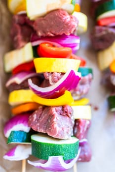 Raw skewers with beef and fresh veggies, wrapped in butcher brown paper, await grilling.