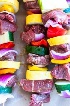 Raw skewers with beef and fresh veggies, wrapped in butcher brown paper, await grilling.