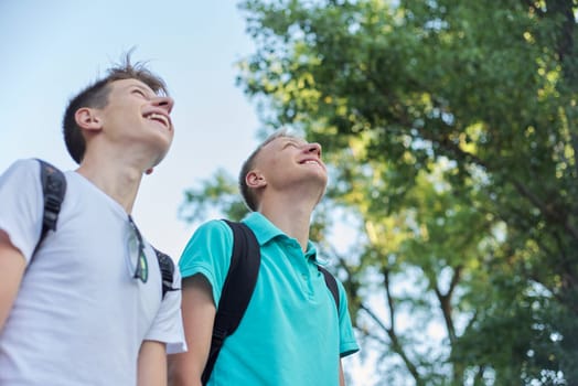 Outdoor portrait of smiling handsome young males, two laughing teenagers looking up