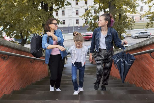 Mother and children two daughters walking on the stairs in autumn city