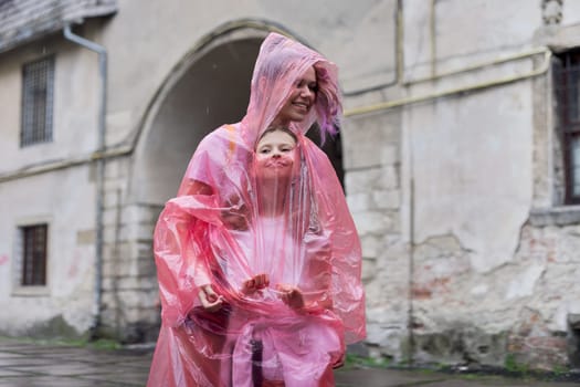 Girls children walking in the tourist city in the rain dressed in a raincoat