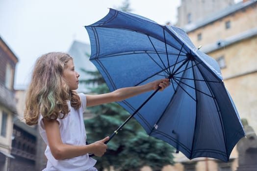 Rainy weather, portrait of beautiful little girl with an umbrella in the city