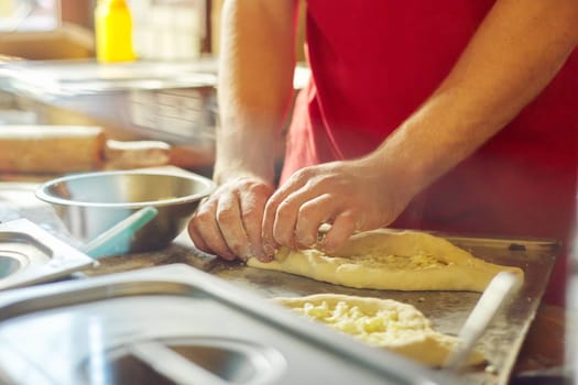 Healthy natural food, hands of man preparing khachapuri, on the table flour dough cheese. Cooking process, culinary, recipe, home bakery.