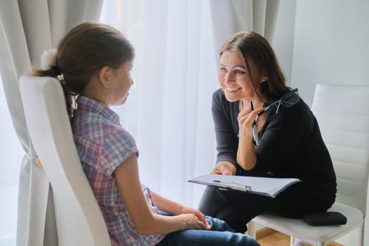 Woman elementary school teacher testing talking to girl. Education, individual learning, child psychology