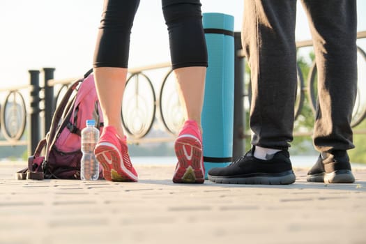 Healthy athletic lifestyle of man and woman, close up of couple legs in sneakers sportswear with water bottle of exercise mat