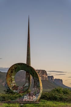 Sculpture with graffiti stands before mountains.