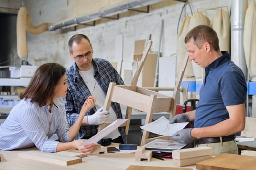 Industrial carpentry workshop, group of working people discussing new model of furniture, wooden modern chair