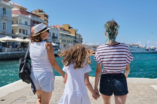 Summer vacation together family mother and daughter children traveling in Mediterranean. Standing with backs on embankment of resort sea town on shore of bay looking at cruise ship