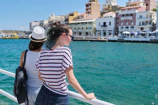 Mediterranean, people women backs near sea promenade, mother and daughter teenager traveling and enjoying sea bay and cityscape