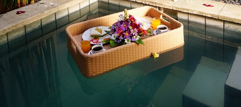 Set of floating breakfast tray in swimming pool. Breakfast in swimming pool, floating breakfast set in tray in resort in Bali