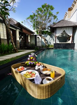 Set of floating breakfast tray in swimming pool. Breakfast in swimming pool, floating breakfast set in tray in resort in Bali