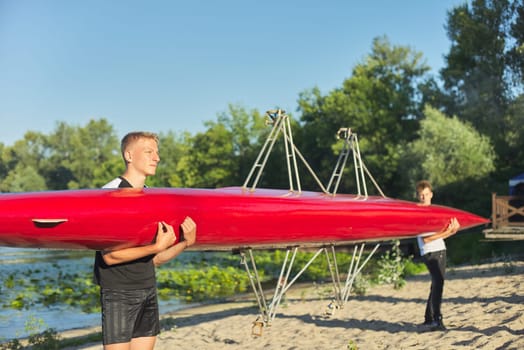 Boys teenagers walking with sports boat kayaking to river, water sports, active healthy lifestyle of young males