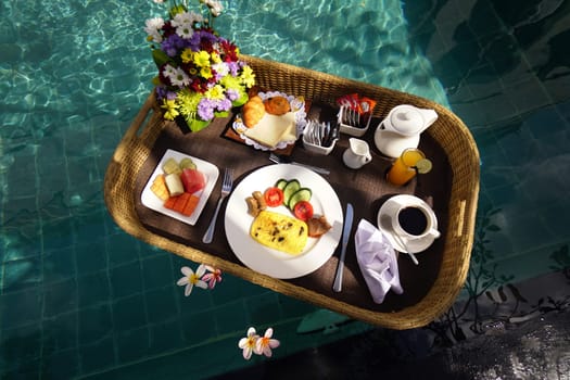 Set of floating breakfast tray in swimming pool. Breakfast in swimming pool, floating breakfast set in tray in resort in Bali