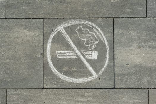 Sign no smoking painted on the grey sidewalk.