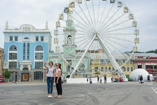 Kyiv UA, 19-07-2018. Young teenage girls are walking the streets of the city. Background Ferris wheel, square of the European city.