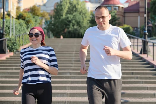 Active healthy lifestyle of mature couple. Middle-aged man and woman running upstairs.