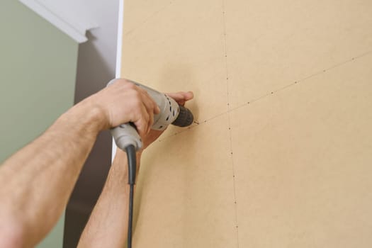 Closeup of hand worker doing furniture, assembling kitchen with professional tools.