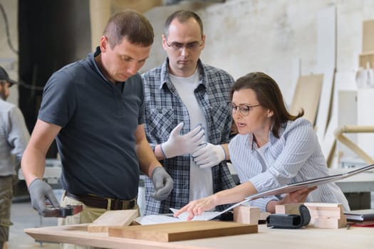 Team of carpenters workshop workers discussing a furniture project with client, designer, engineer. Group of people in carpentry workshop