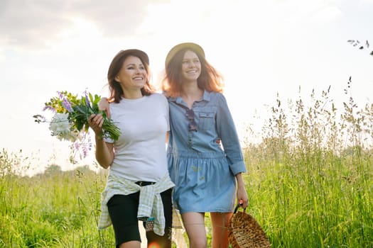 Summer portrait of happy mother and daughter on the nature in the meadow, golden hour