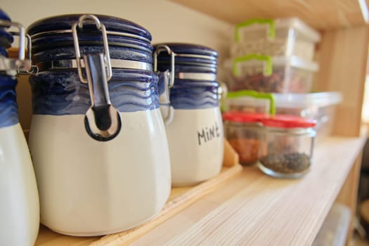 Wooden shelves with food and kitchen utensils in the pantry.