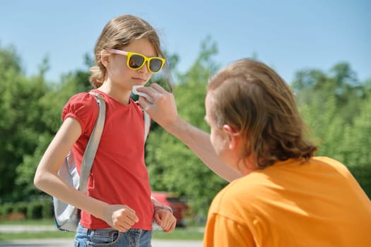 Outdoor summer portrait of father and daughter, caring dad helps his child, wipes his lips soiled with ice cream