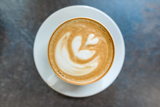 Top view, latte art, cup of coffee on gray stone tabletop.