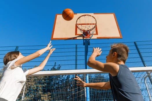 Streetball basketball game with two players, teenagers girl and boy with ball, outdoor city basketball court