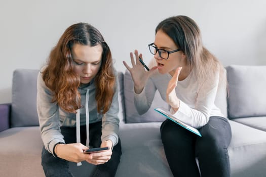 Young woman professional psychologist talking with teenager girl 14, 15 years old sitting in office on sofa. Mental health of child in adolescence.