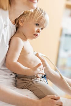 Small child being checked for heart murmur by heart ultrasound exam by cardiologist as part of regular medical checkout at pediatrician