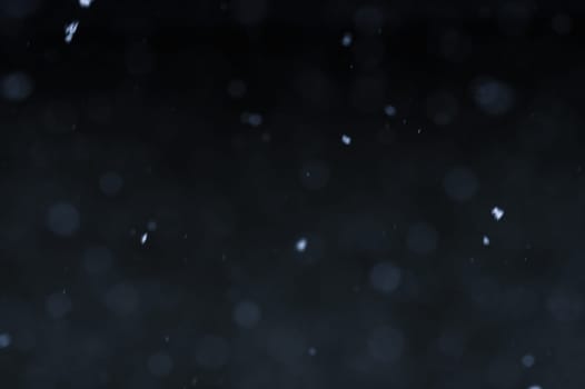 Falling snowflakes on night sky background, isolated for post production and overlay in graphic editor. Bokeh of white snow on a black background.