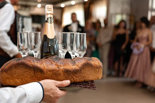 Traditional wedding kalach at a wedding in Ukraine, brides and wedding ceremonies. Waiter serves champagne with glasses.