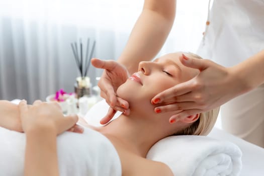 Caucasian woman enjoying relaxing anti-stress head massage and pampering facial beauty skin recreation leisure in dayspa modern light ambient at luxury resort or hotel spa salon. Quiescent