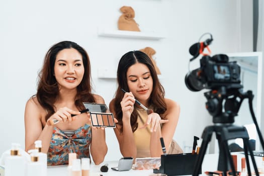 Asian Woman influencer shoot live streaming vlog video review makeup uttermost social media or blog. Happy young girl with cosmetics studio lighting for marketing recording session broadcasting online