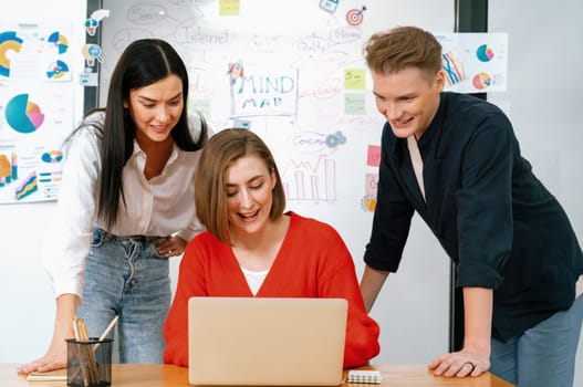 Professional business team working together by using laptop in start up project at meeting in front of glass board with mind map while colleague brainstorm and discuss about strategy. Immaculate.