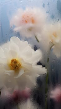 Background of blooming flowers in front of glass with water drops.