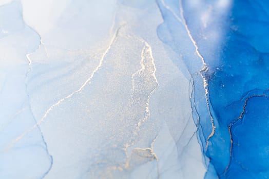 Blue and gold alcohol ink. Style incorporates the swirls of marble or the ripples of agate. Abstract painting, trendy background for wallpapers, posters, cards, invitations, websites.