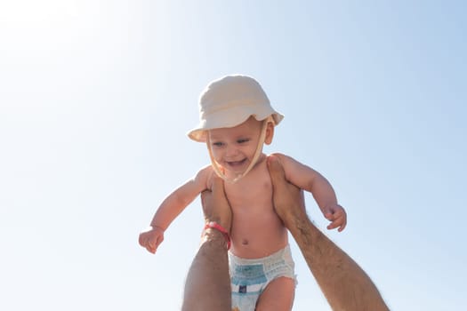 In a sun-kissed setting, a father joyfully lifts his baby towards the sky, capturing the essence of love and play. Concept of family bonding and joyful childhood